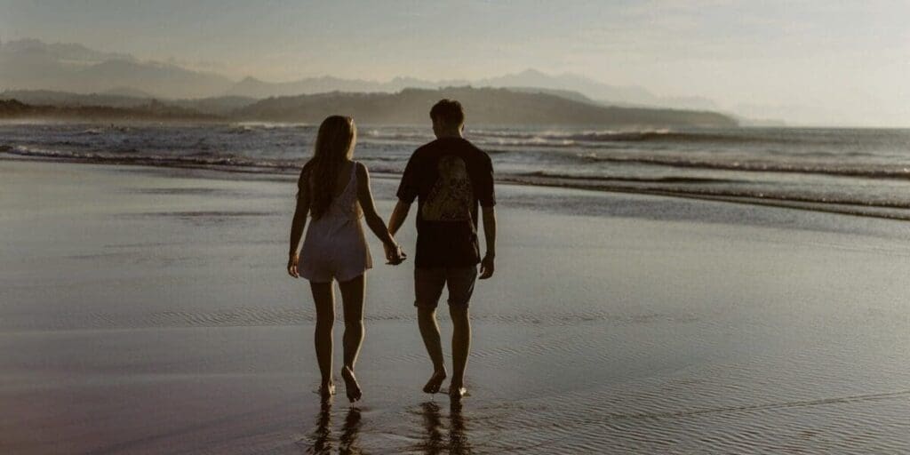 Couple Holding Hands Walking on the Beach