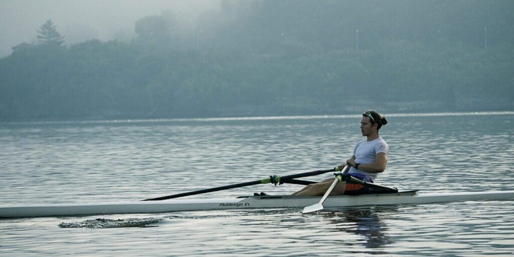 Man Rowing Across a Calm Lake - Rowing Workout Exercise